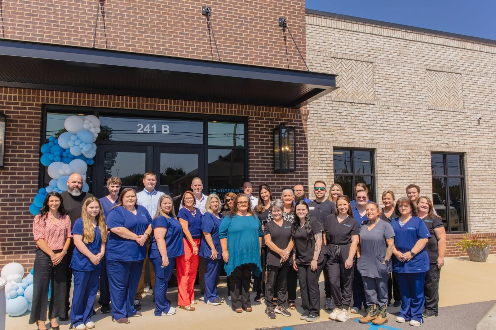 VuePoint colleagues in blue and black scrubs gathered outside the Gadsden office entrance